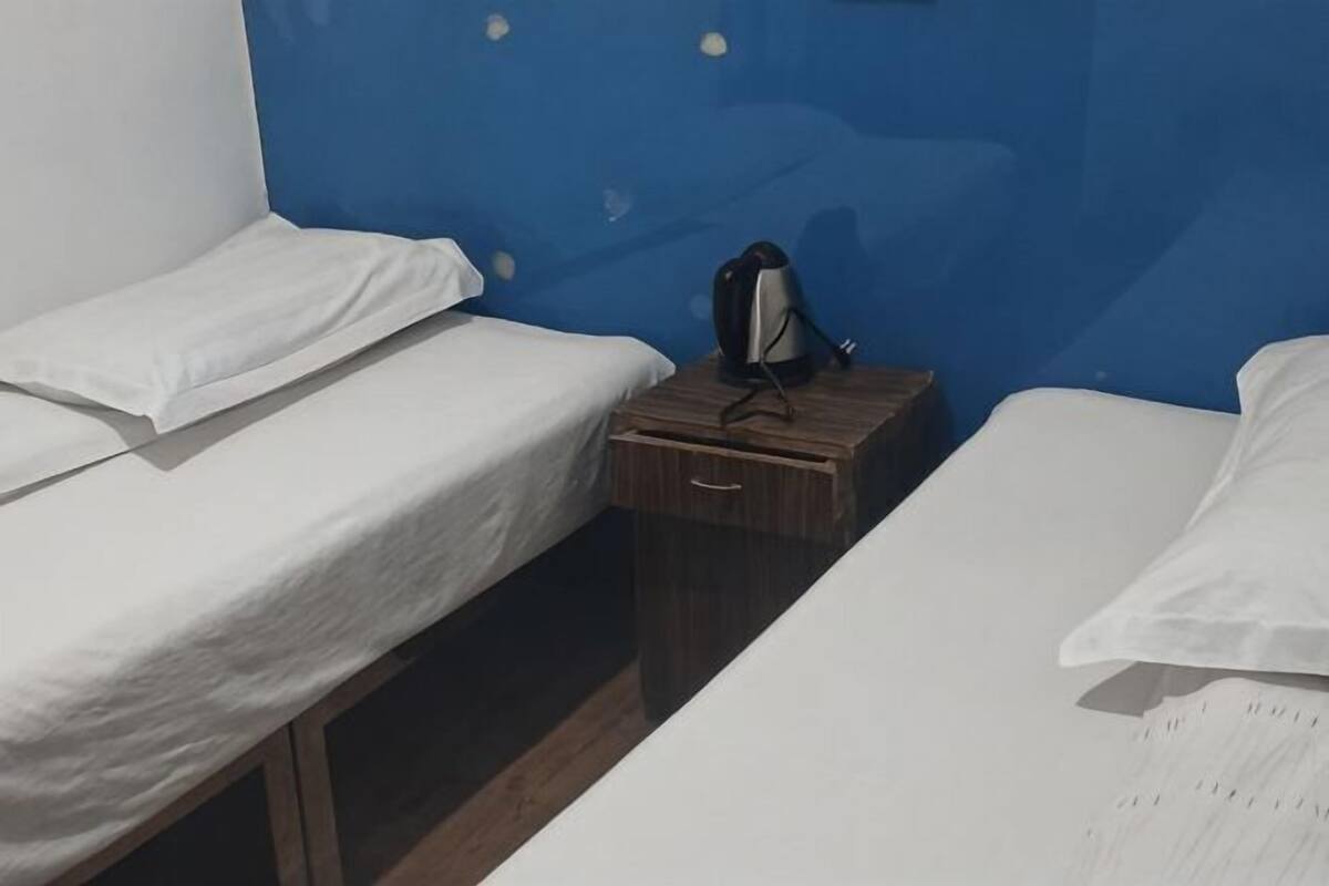 Une chambre avec deux lits, une table de chevet en bois et un mur bleu.