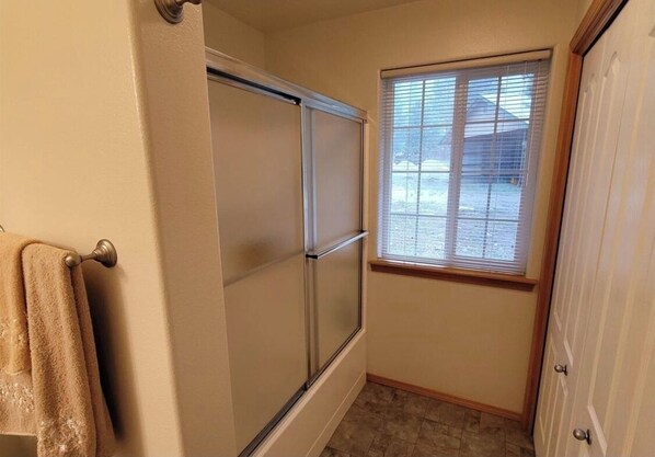 A bathroom with a shower, a window, and a towel rack.