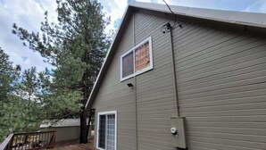 A two-story building with a wooden deck, a window, and a door. - Charming 3-bedroom house in the beautiful mountains of Pine, Idaho. (Mountain Home)