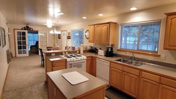 A kitchen with wooden cabinets, a stove, a dishwasher, and a large window. - Charming 3-bedroom house in the beautiful mountains of Pine, Idaho. (Mountain Home)