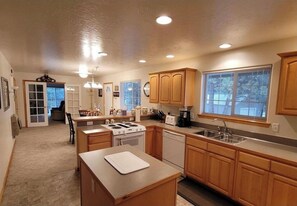A kitchen with wooden cabinets, a stove, a dishwasher, and a large window.