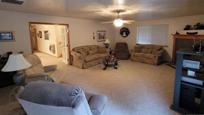 A living room with two sofas, a coffee table, a ceiling fan, and a fireplace. - Charming 3-bedroom house in the beautiful mountains of Pine, Idaho. (Mountain Home)