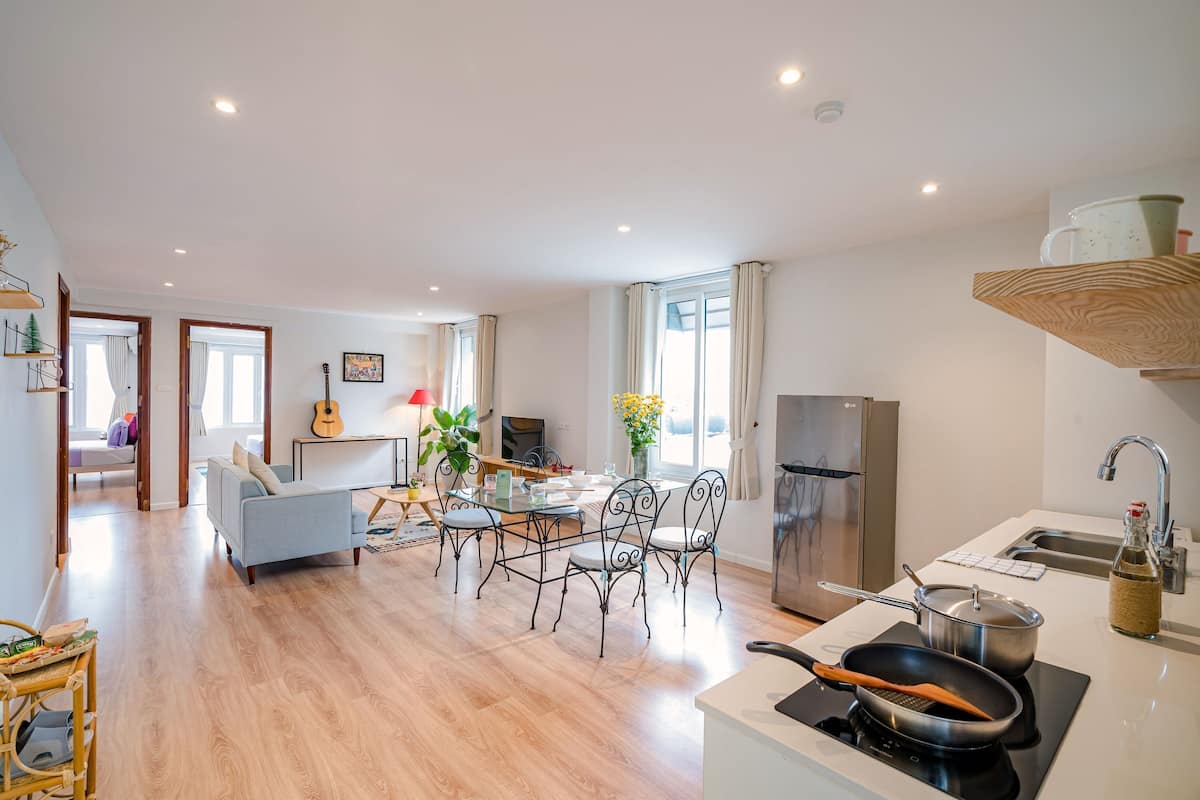 Une cuisine moderne avec un coin repas, un plancher en bois et un réfrigérateur visible.