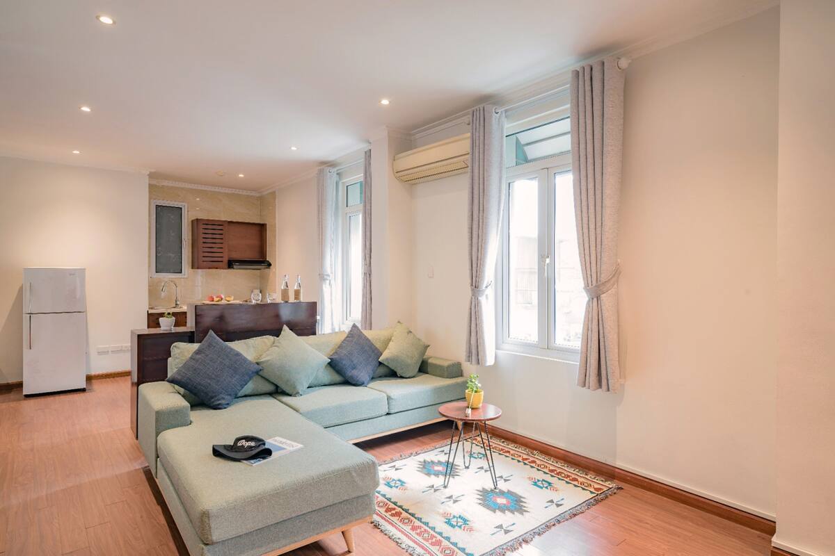 Un salon moderne avec un canapé, une petite table et un coin cuisine à l’arrière-plan.