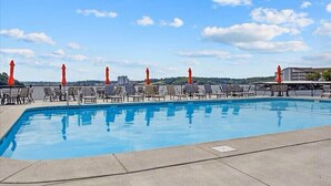 Ein Swimmingpool mit Liegestühlen und Blick auf eine Brücke sowie Gebäude im Hintergrund.
