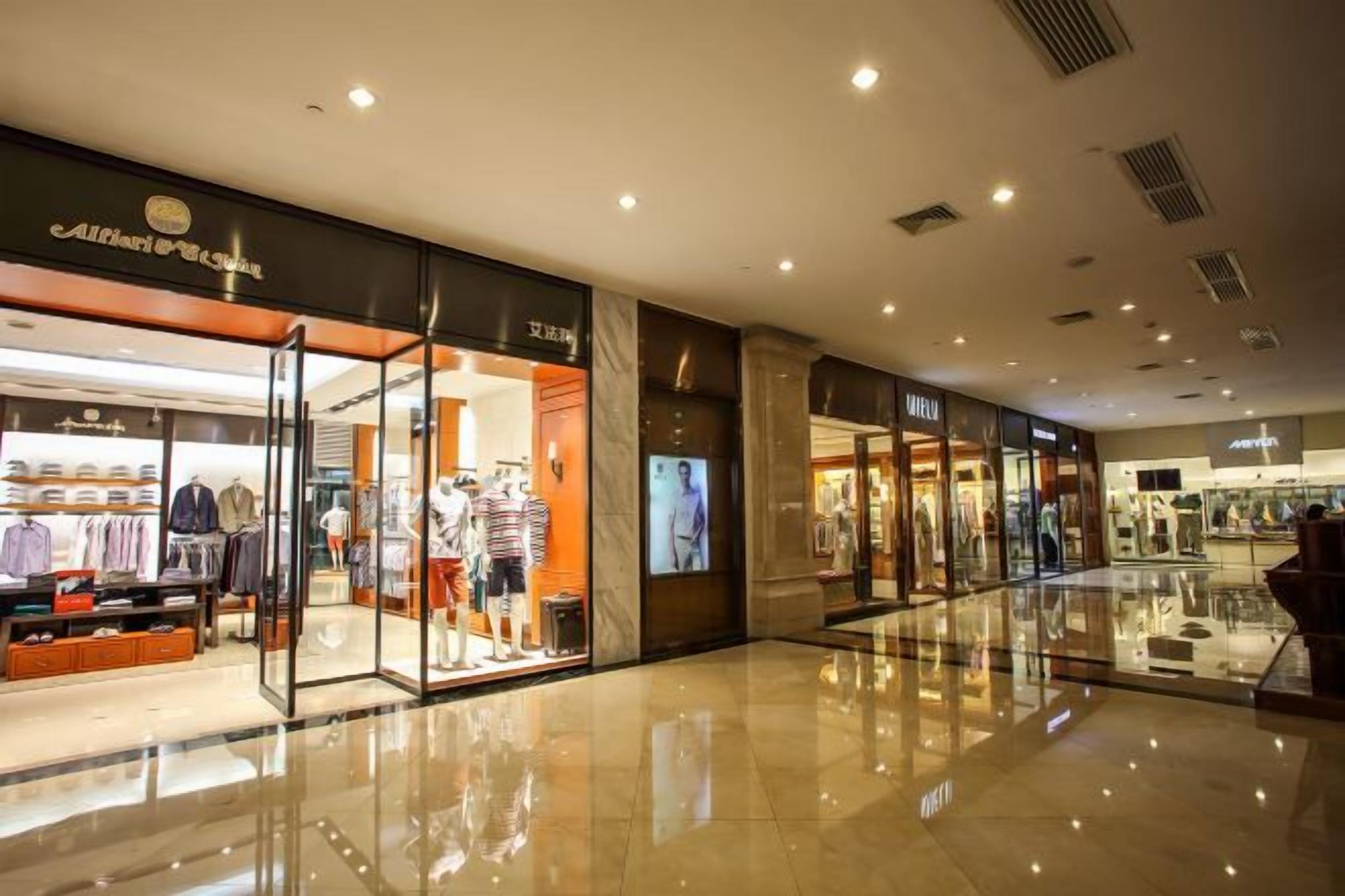 L’intérieur d’un centre commercial moderne, avec un magasin de vêtements à gauche et un magasin de chaussures à droite.