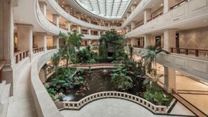 A multi-level atrium with a central water feature surrounded by lush greenery and a glass ceiling. - Zhanjiang Shanhe Hotel (Zhanjiang)