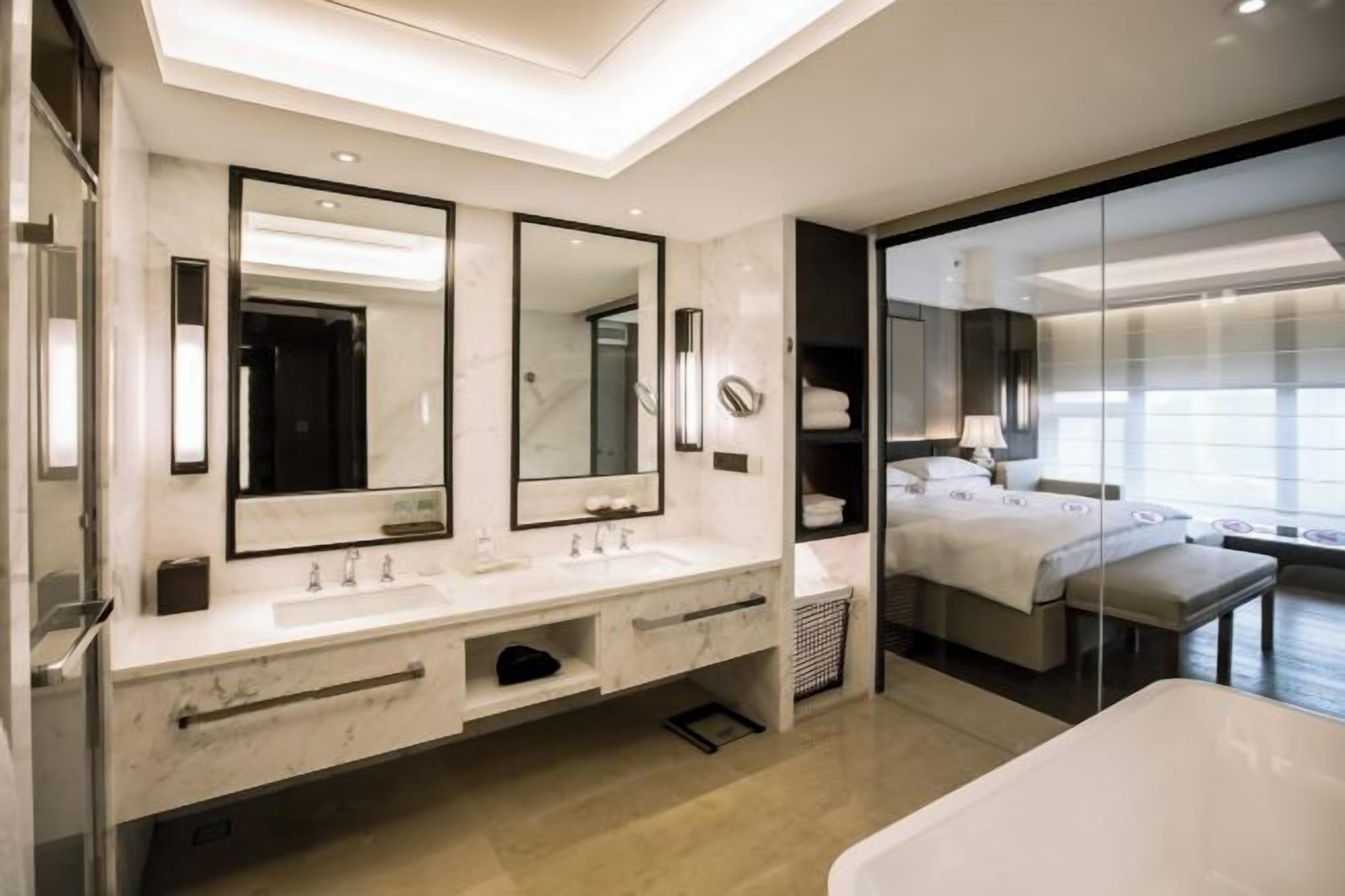 A modern bathroom with a large mirror, a bathtub, and a shower area.