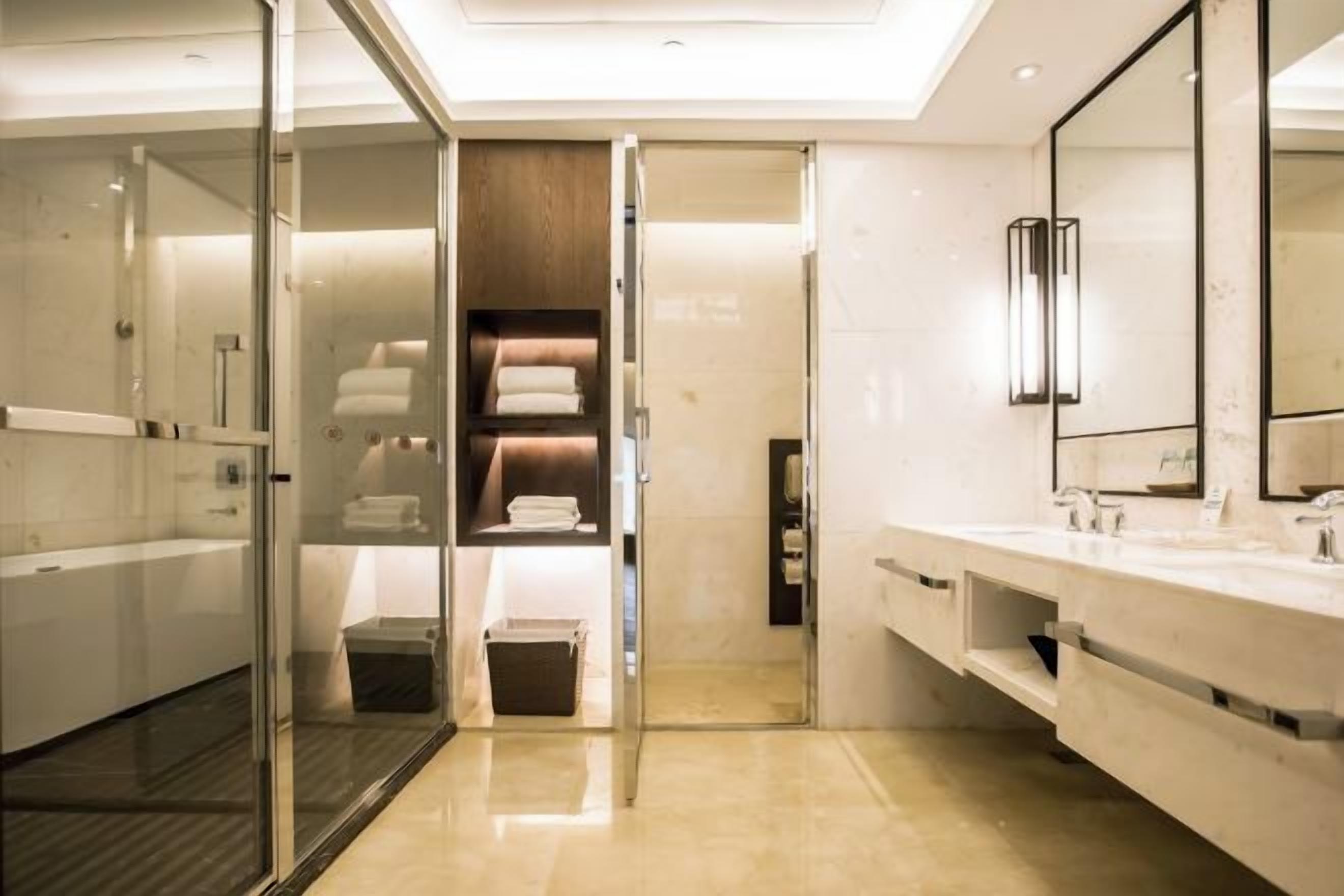 A modern bathroom with a glass shower enclosure, a vanity with a mirror, and a built-in storage unit.