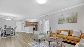 A spacious living room with a sofa, coffee table, and a dining area with chairs and a table.
