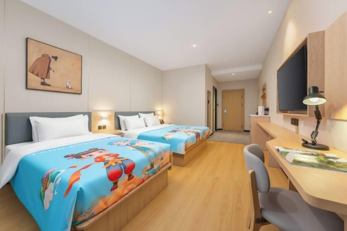 A hotel room with two beds, a desk, and a chair.