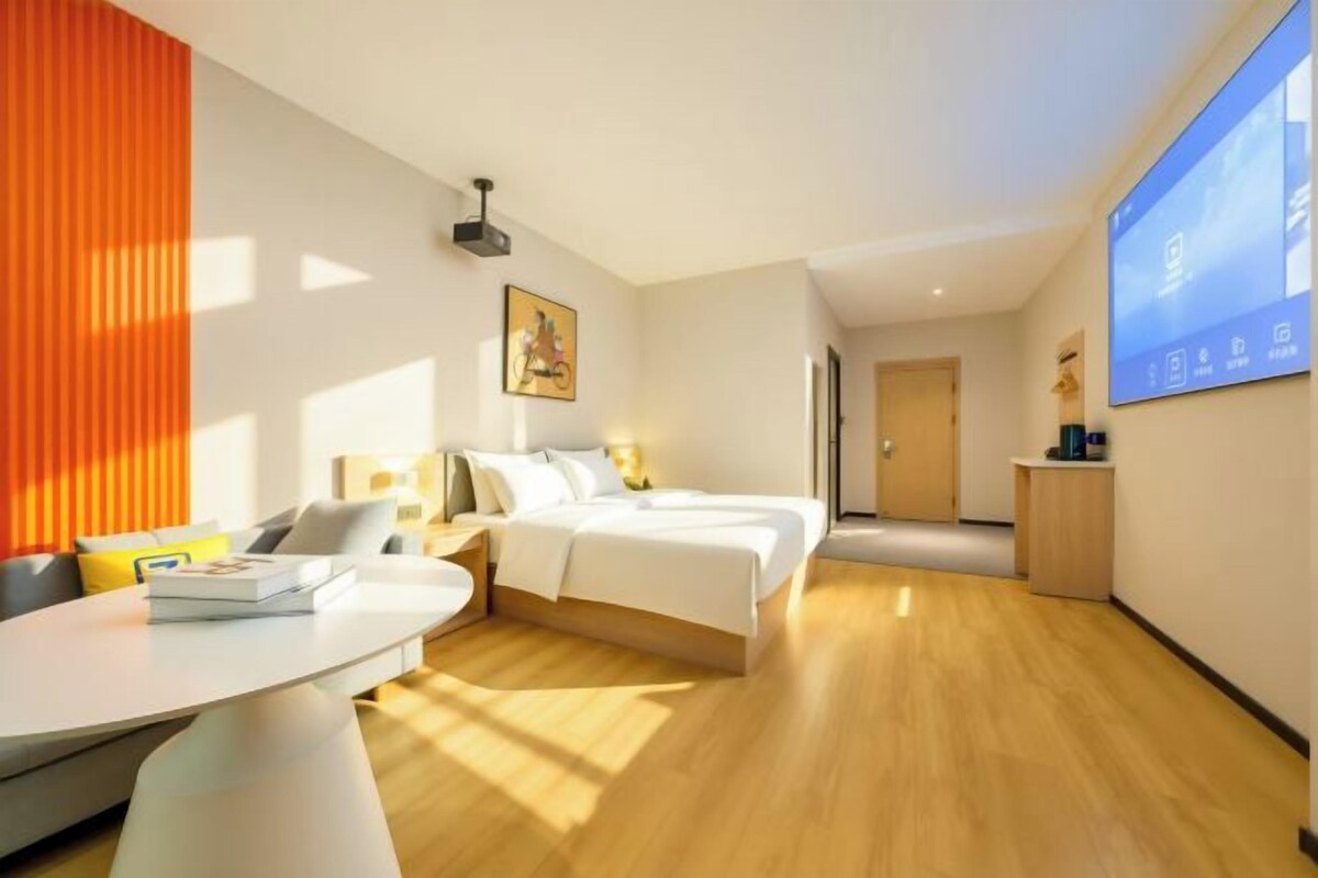 A modern hotel room with a bed, a desk, and a seating area.