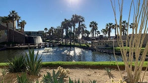 Un resort con una fuente de agua, palmeras y cielo despejado.
