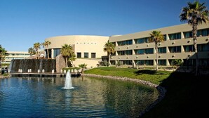 Un hotel con piscina, palmeras y una cascada.