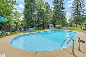 A swimming pool with a metal ladder, surrounded by a fence, and trees in the background. - New Studio Walkable to Lake & Village w/ Pool! (Hammondsport)