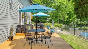 Une terrasse extérieure avec une table et des chaises, un parasol bleu et une piscine en arrière-plan.