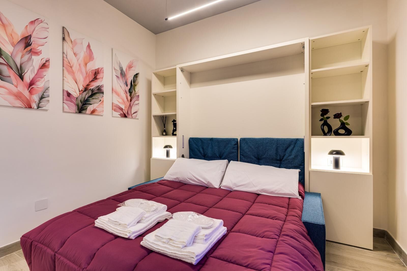 Ein modernes Schlafzimmer mit einem großen Bett, Einbauschränken und dekorativer Wandkunst.