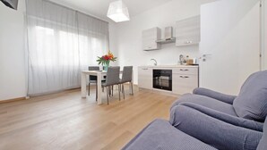 A modern apartment with a dining area, kitchenette, and a seating area with a sofa.