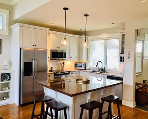 A modern kitchen with a central island, stainless steel appliances, and pendant lighting.