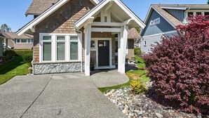A two-story house with a stone foundation, a front porch, and a well-maintained lawn.