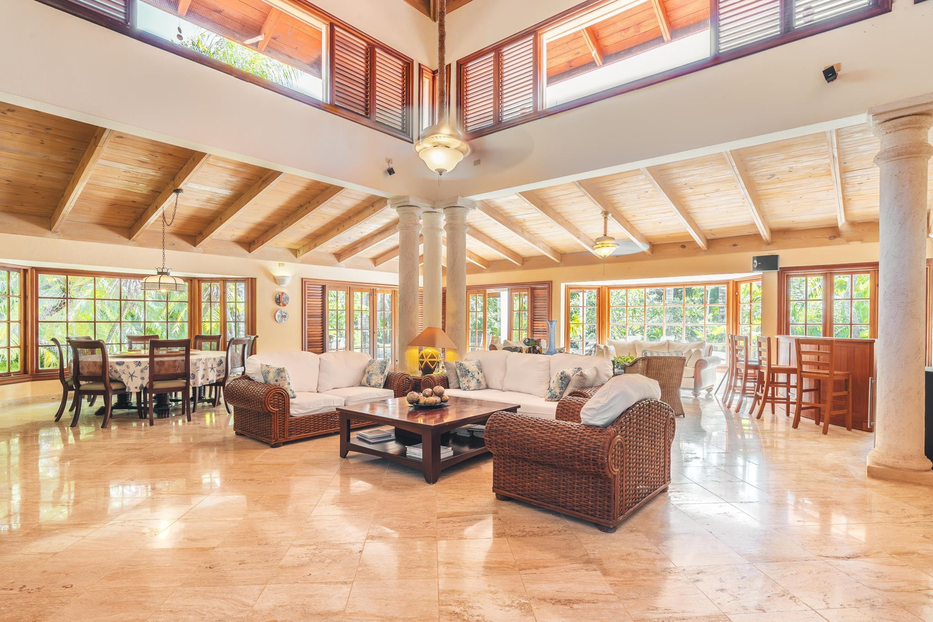 A spacious living area with high ceilings, large windows, and a central seating area with a coffee table and sofas.