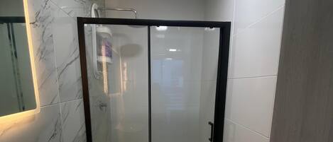 A modern bathroom with a glass-enclosed shower, a white toilet, and a sink.