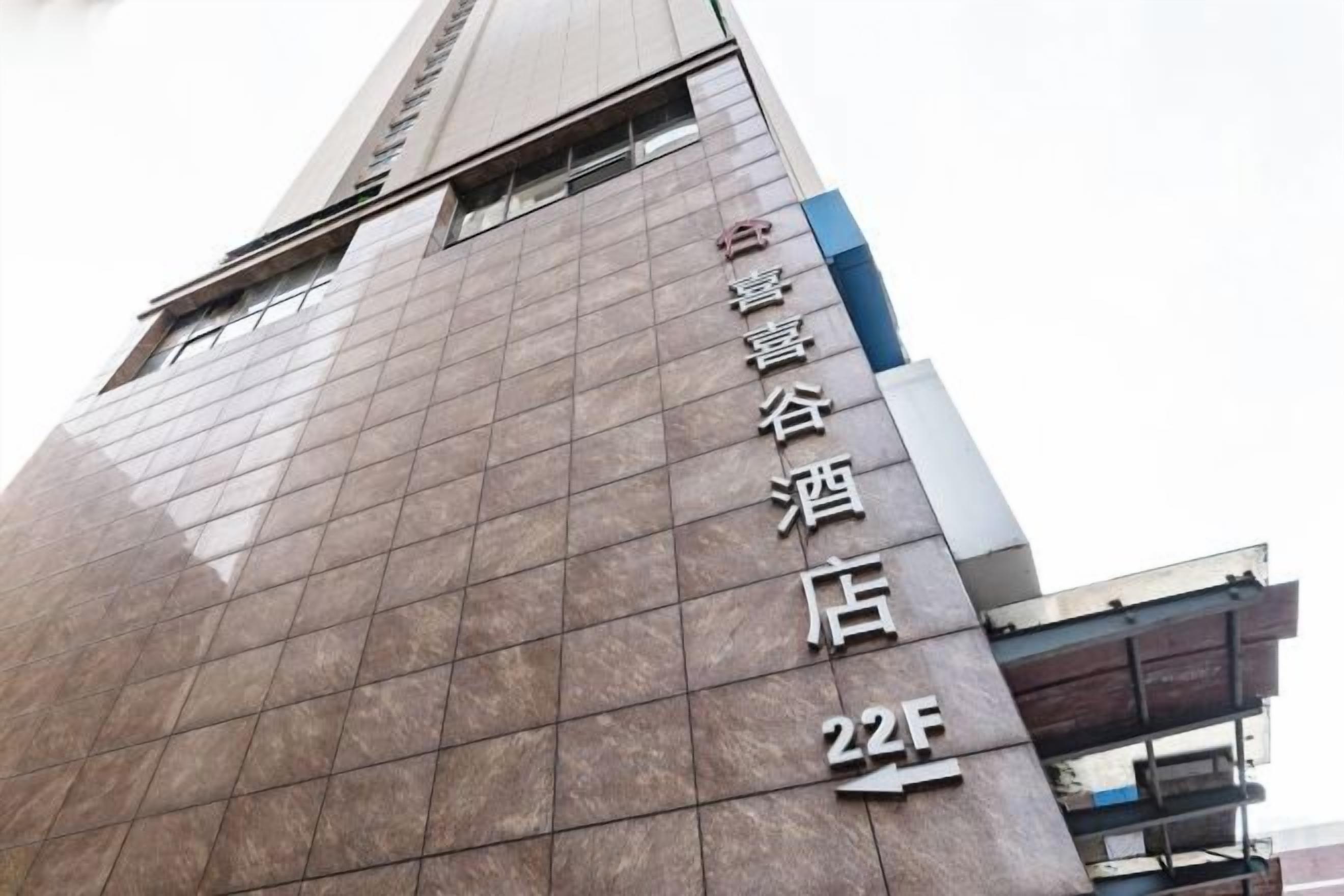 Un edificio alto con fachada reflectante y un cartel que indica un hotel llamado 'Xinghuai Valley Hotel' en el piso 224.