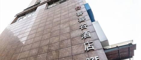 Un edificio alto con fachada reflectante y un cartel que indica un hotel llamado 'Xinghuai Valley Hotel' en el piso 224.