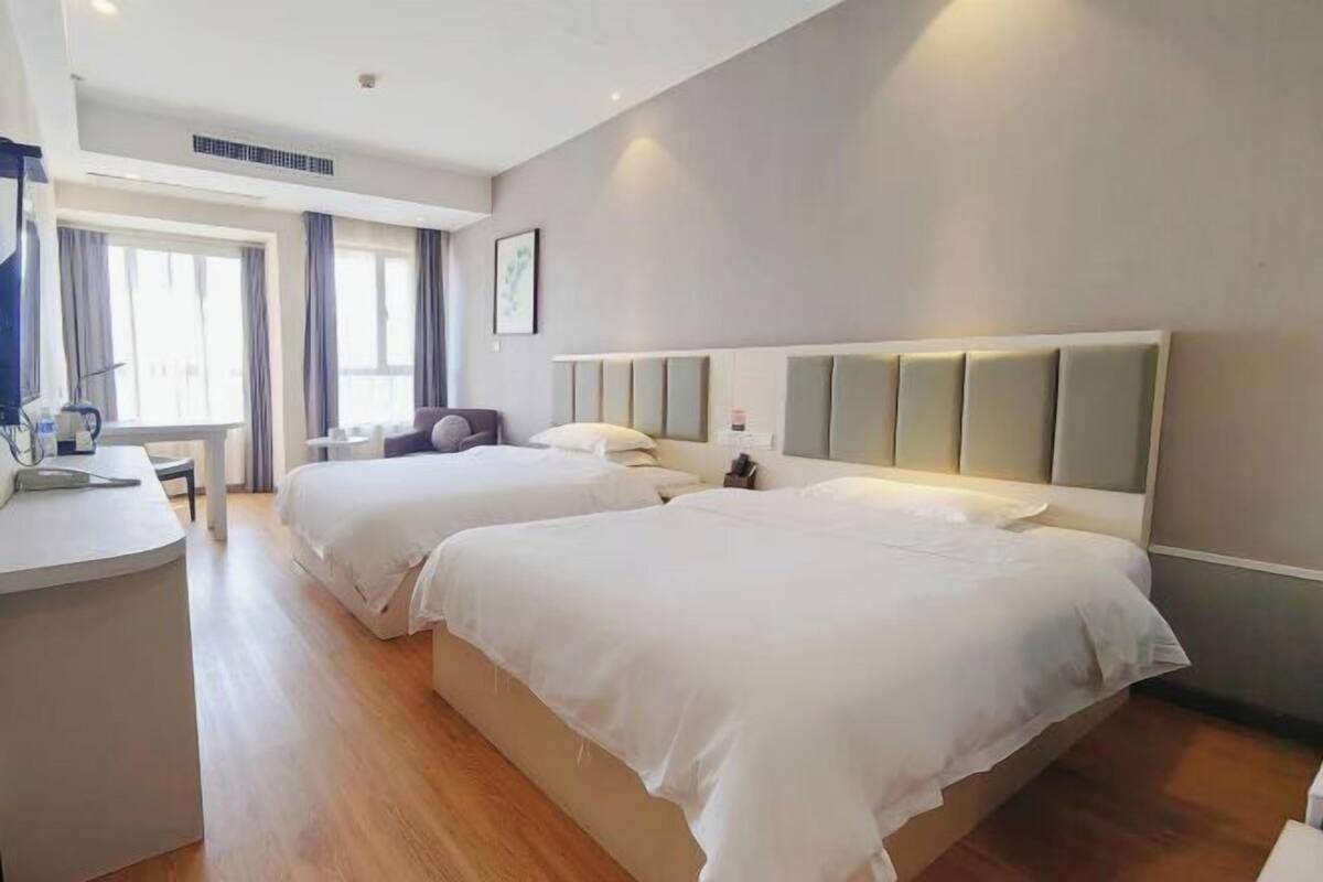 A hotel room with two beds, a desk, and a chair.