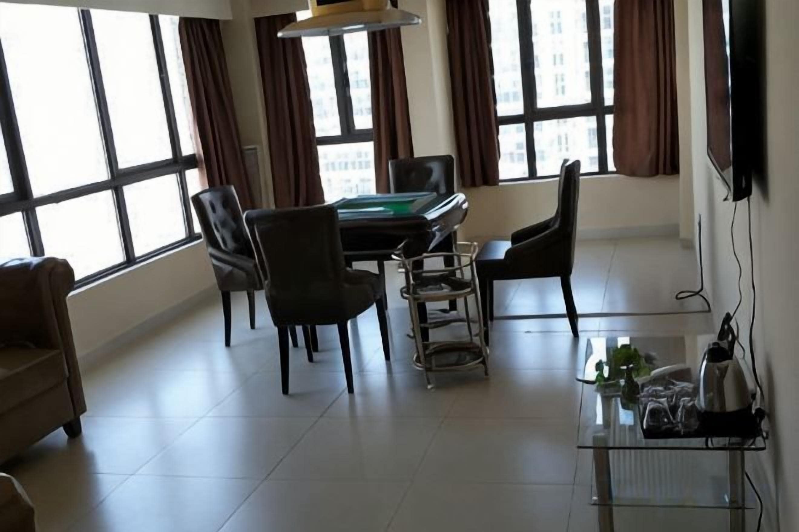Una habitación con mesa de billar, sillas, televisor y ventanas amplias.