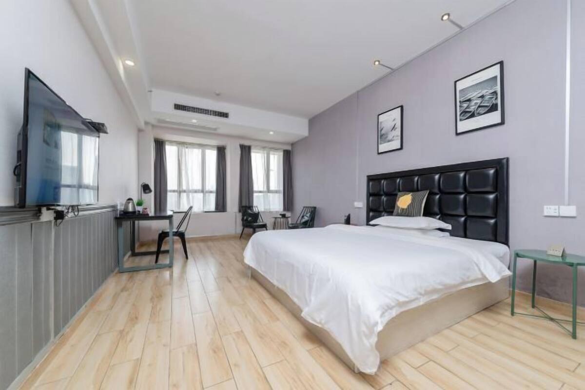 A modern bedroom with a large bed, a desk, and a television.