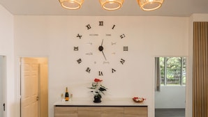 A modern kitchen with a wooden cabinet, a clock on the wall, and a fruit centerpiece on the counter.