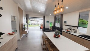 A modern kitchen with a long dining table, wooden chairs, and a built-in stove.