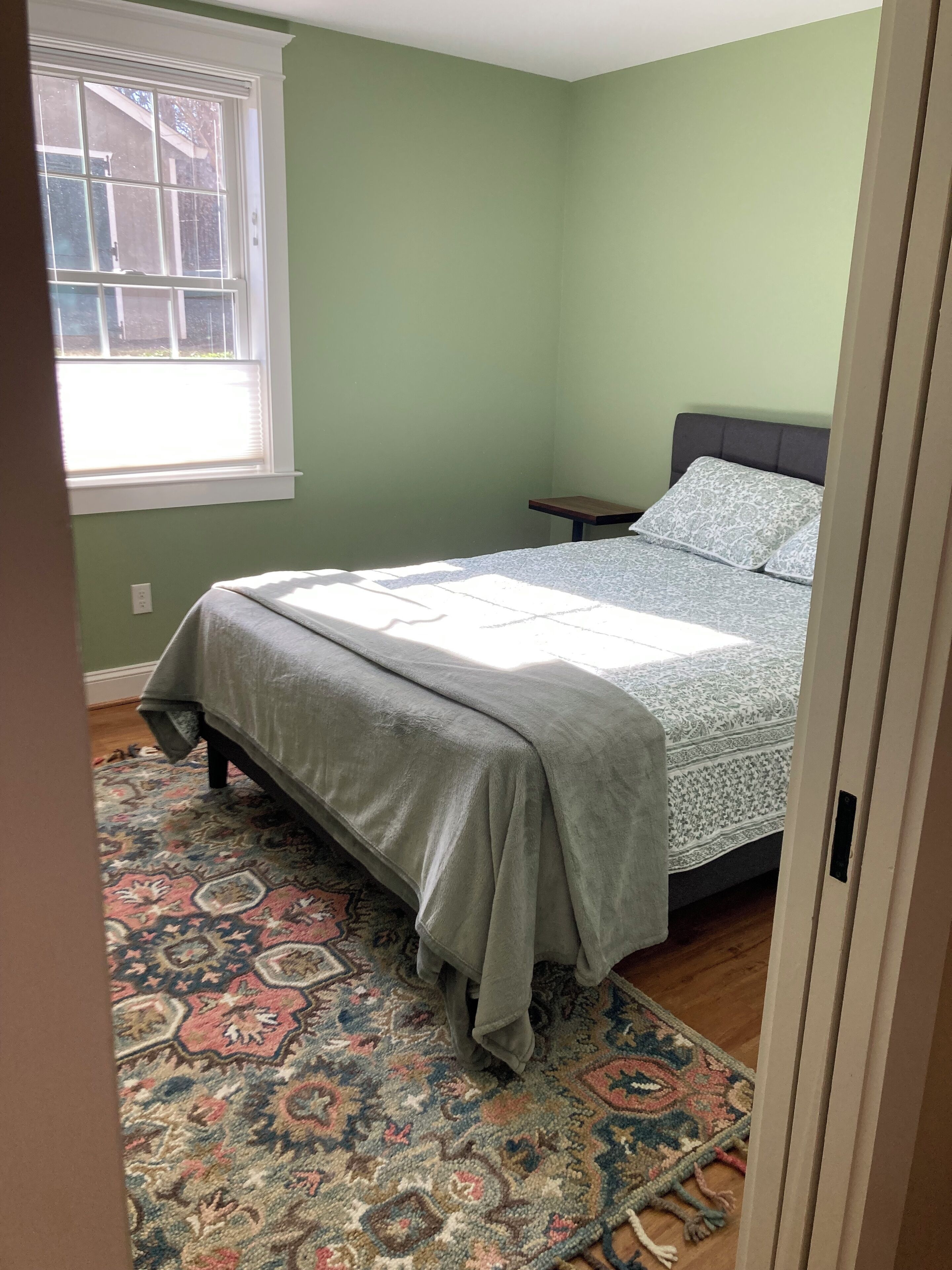 Une chambre à coucher avec un lit, une table de chevet et un tapis à motifs.