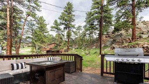 A deck with outdoor furniture, a grill, and a view of a forested area. - Lux 3BR home - Views/Wildlife/RMNP/Shop/Snowshoe (Estes Park)