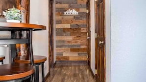 A hallway with a wooden floor, a bar area with stools, and a wall-mounted clock. - Lux 3BR home - Views/Wildlife/RMNP/Shop/Snowshoe (Estes Park)