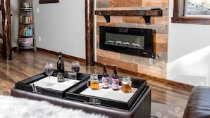 A living room with a fireplace, a bookshelf, and a coffee table with drinks and a board game. - Lux 3BR home - Views/Wildlife/RMNP/Shop/Snowshoe (Estes Park)