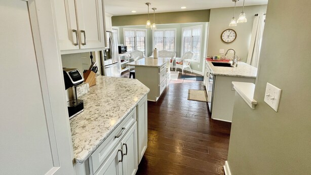A modern kitchen with white cabinets, a marble countertop, and a central island. - 5-Bedroom Estate – 12 acres, Huge Space, Fast WiFi, Fitness Room, & More! (Williamston)