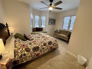 Une chambre à coucher avec un grand lit, un canapé vert, un ventilateur de plafond et une fenêtre donnant sur un beau paysage.