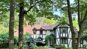 A Tudor-style house with a stone facade, multiple gables, and a well-maintained lawn. - 5-Bedroom Estate – 12 acres, Huge Space, Fast WiFi, Fitness Room, & More! (Williamston)