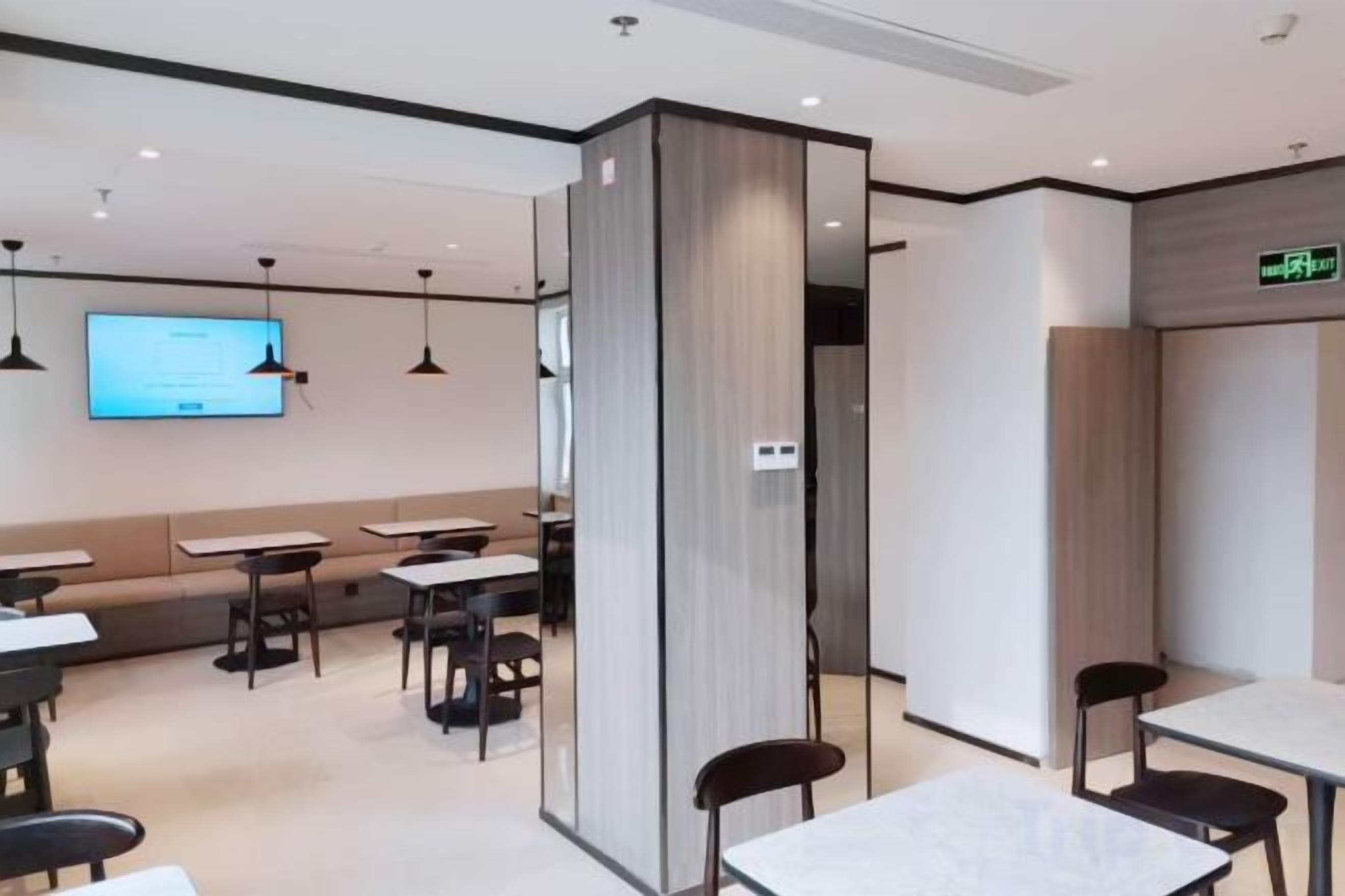 A modern dining area with tables and chairs, a projection screen, and a wooden partition.