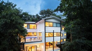 A multi-story modern house with balconies, large windows, and a well-lit interior. - Casa Dos Cascadas - Luxury & Jungle (Manuel Antonio)