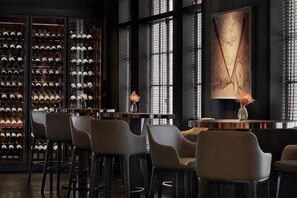 A bar area with a wine rack, bar stools, and a large abstract painting. - Wanbai Hotel (Shanghai Hongqiao Airport National Convention and Exhibition Center) (Shanghai)