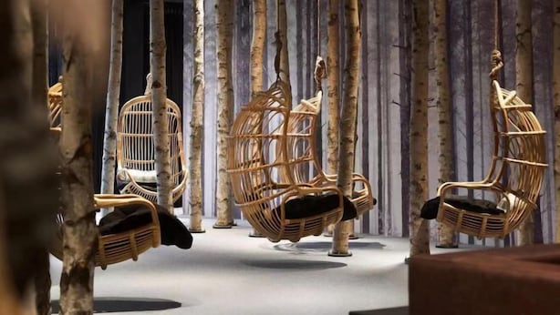 Une pièce avec des chaises en osier suspendues au plafond, un plancher en bois et un décor composé de lattes de bois verticales.