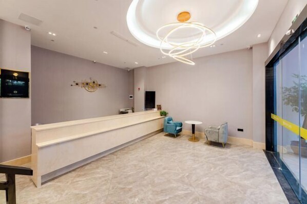 Un'accoglienza moderna con una lunga scrivania della reception, una sedia blu e un'originale lampada a sospensione circolare al soffitto.