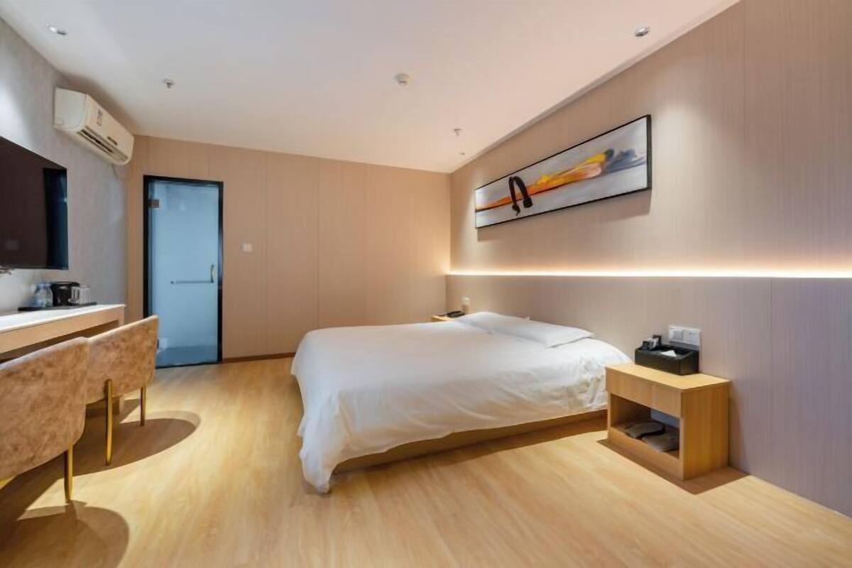 A modern bedroom with a bed, bedside table, and a desk with chairs.