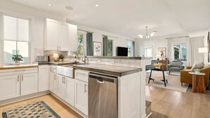 Une cuisine moderne avec des meubles blancs, un lave-vaisselle en acier inoxydable et un grand îlot central.