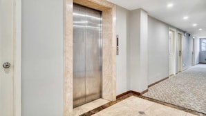 A hallway with an elevator, light-colored walls, and patterned flooring. - Home Inn (Shanghai Qingpu Chengzhong North Road Shiji Lianhua Plaza) (Shanghai)