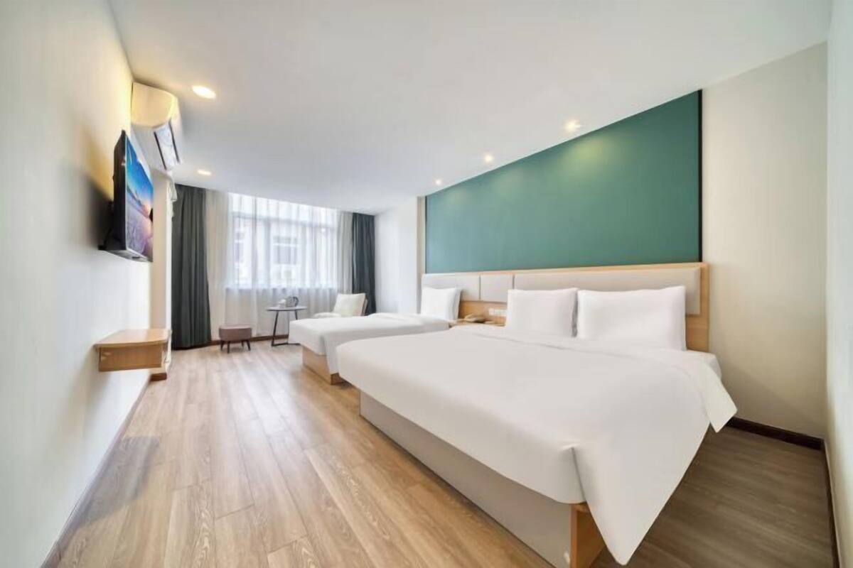 A hotel room with two beds, a desk, a chair, and a TV.