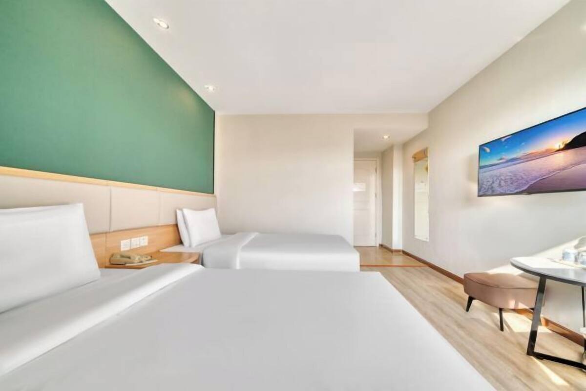 A hotel room with a large bed, a desk, a chair, and a painting on the wall.